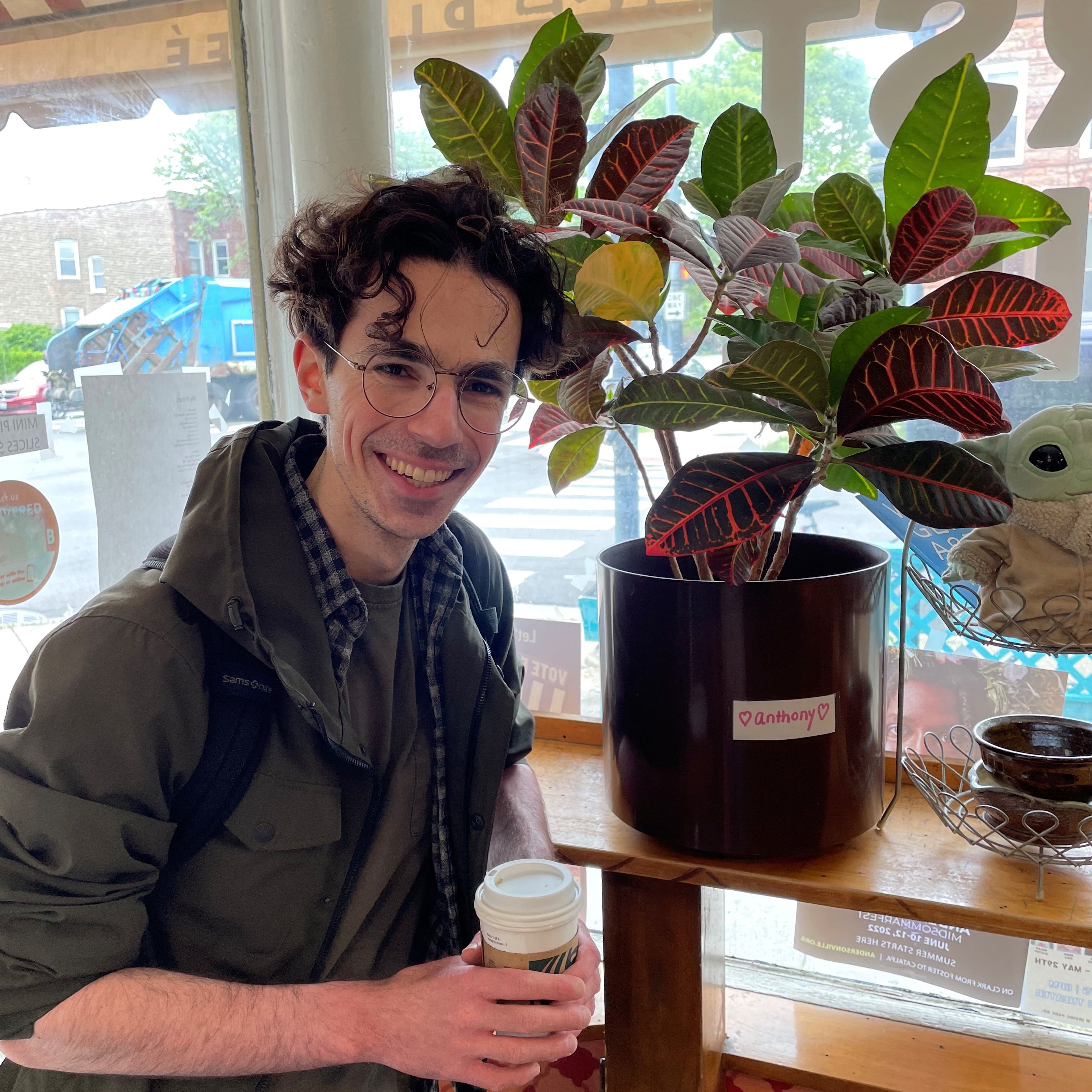 Smiling man indoors standing next to plant