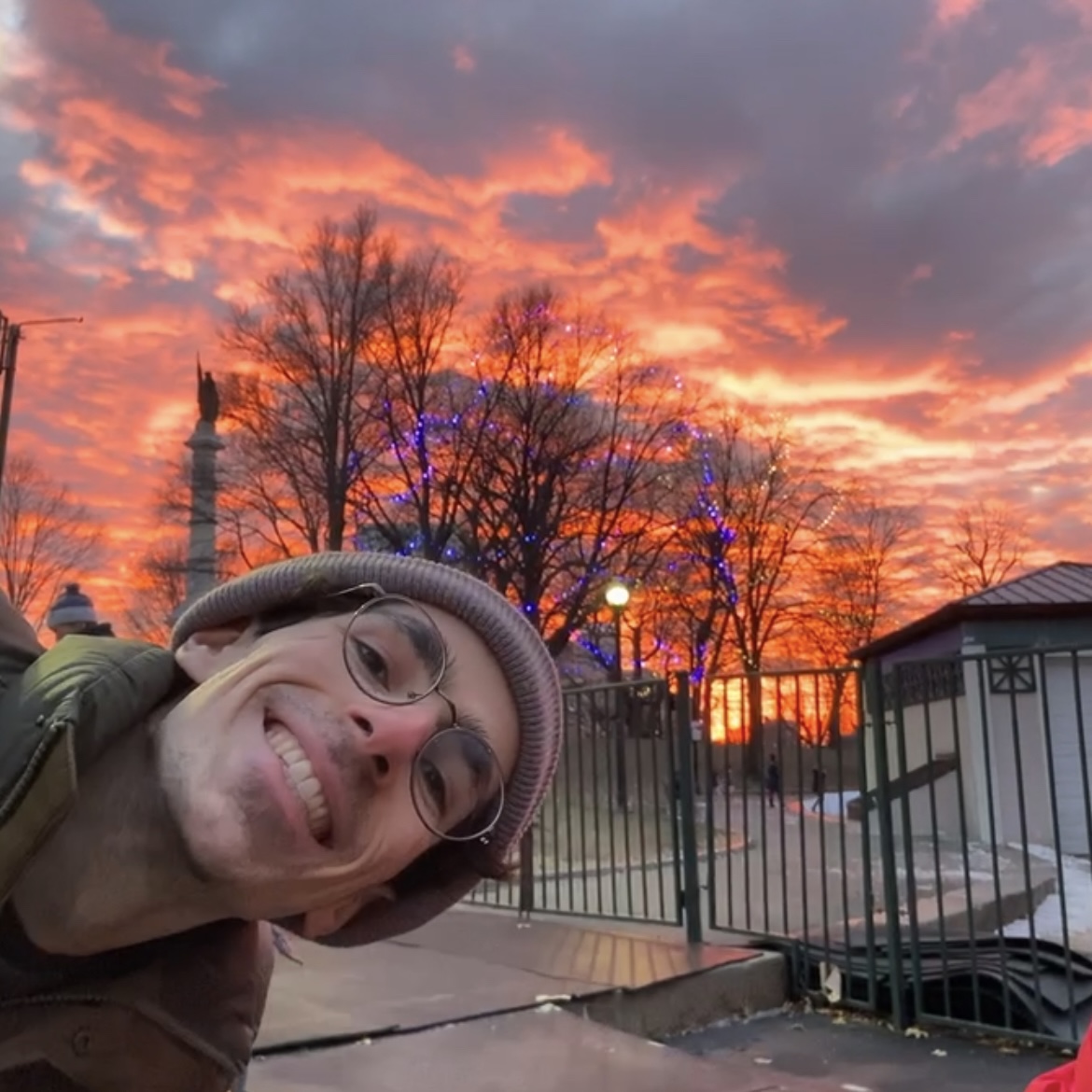 Man in beanie hat smiling in front of sunset